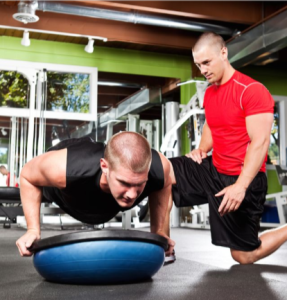 Personal trainer helping an athlete to perform stability push-ups